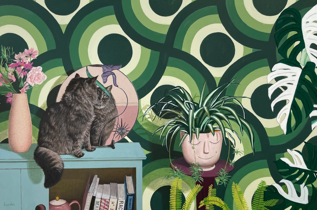Oil painting of Shirley the cat, looking at herself in an Art Nouveau mirror as she sits on a bureau containing books and a teapot. A vase of flowers is beside her to the left. On the far right is a variegated monstera and in the bottom right quarter is a planter that looks like a smiling face with closed eyes with a spider plant for hair. Fish bone ferns come up from the bottom of the painting below it.